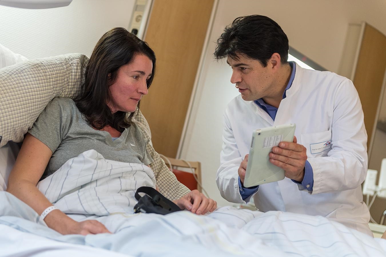 Ein Arzt erklärt einer Patientin etwas mithilfe eines Tablets