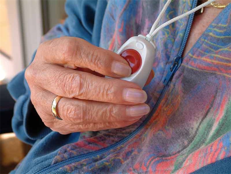 Seniorin hält den Notrufknopf, den sie um den Hals trägt / Foto: fotolia.de