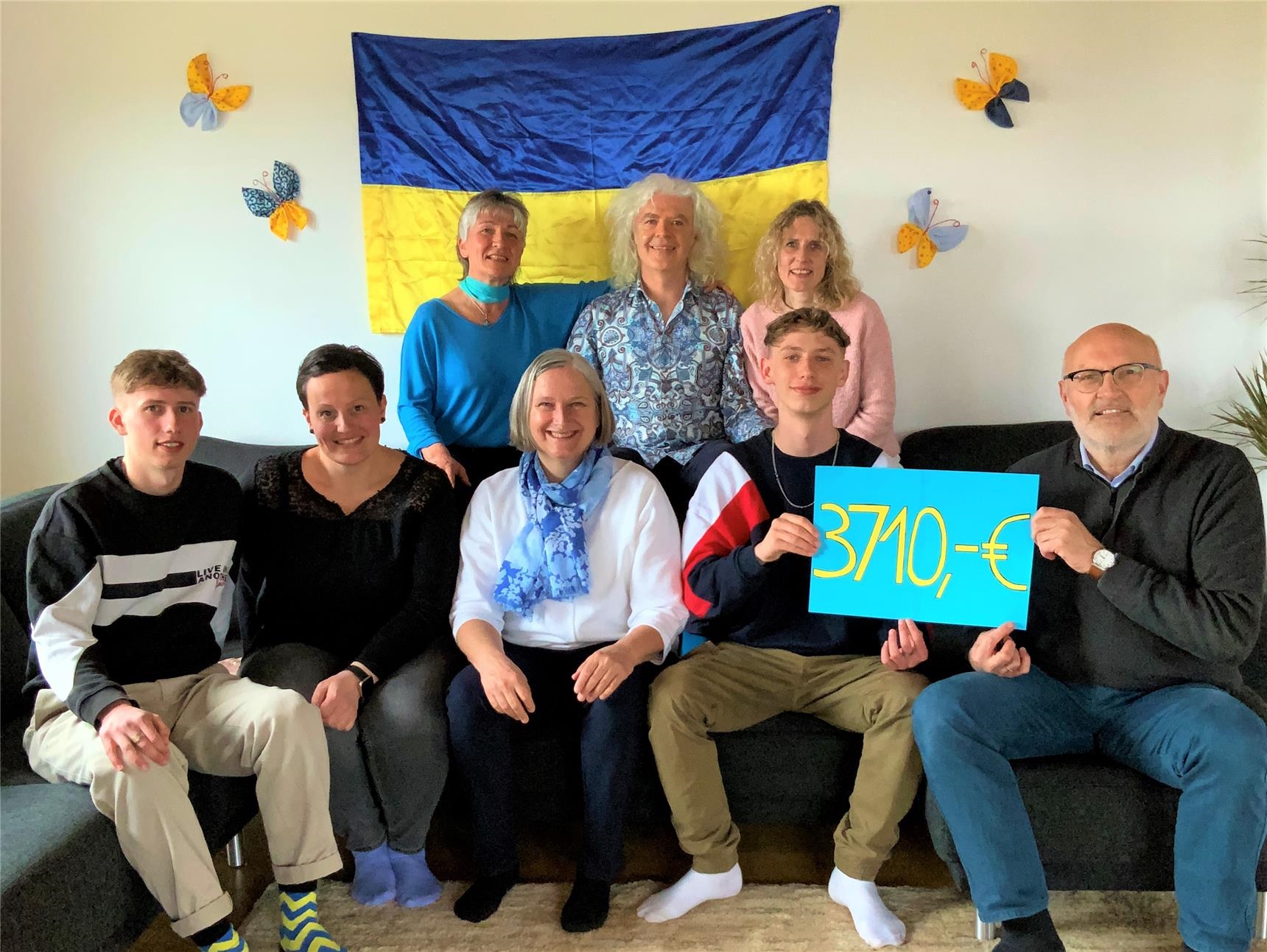acht Männer und Frauen stehen und sitzen vor einer ukrainischen Fahne (Alfons Jeggle)