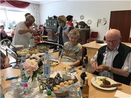 Senioren bei gedeckten Tischen mit Grillwürstchen und Salat / Foto: Caritashaus St. Vincenz