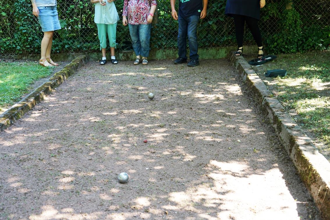 Blick auf eine Boule-Bahn: zwei Kugeln, im Hintergrund mehrere Menschen (Caritasverband Trier e. V.)