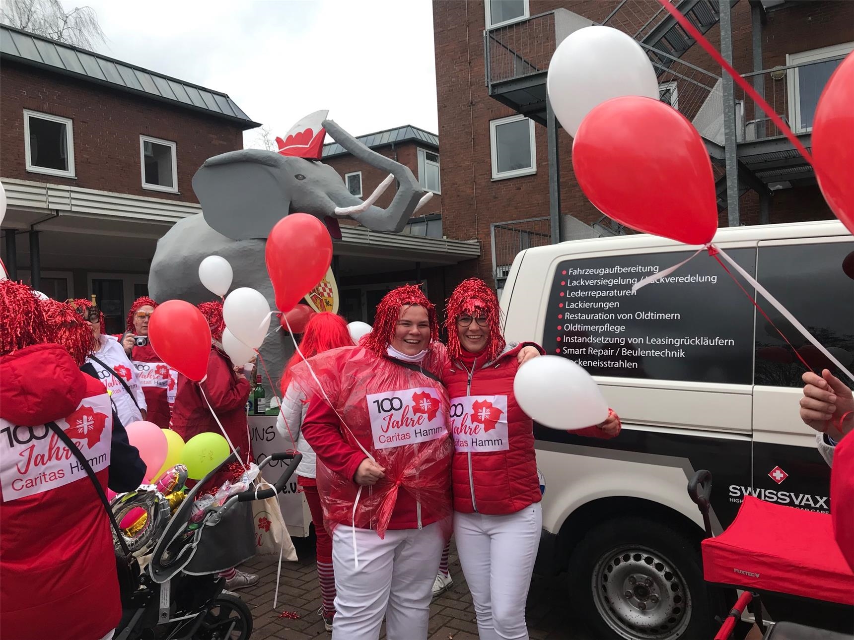Rot-weiß gekleidete Frauen mit roten Perücken und Luftballons (Caritas Hamm)