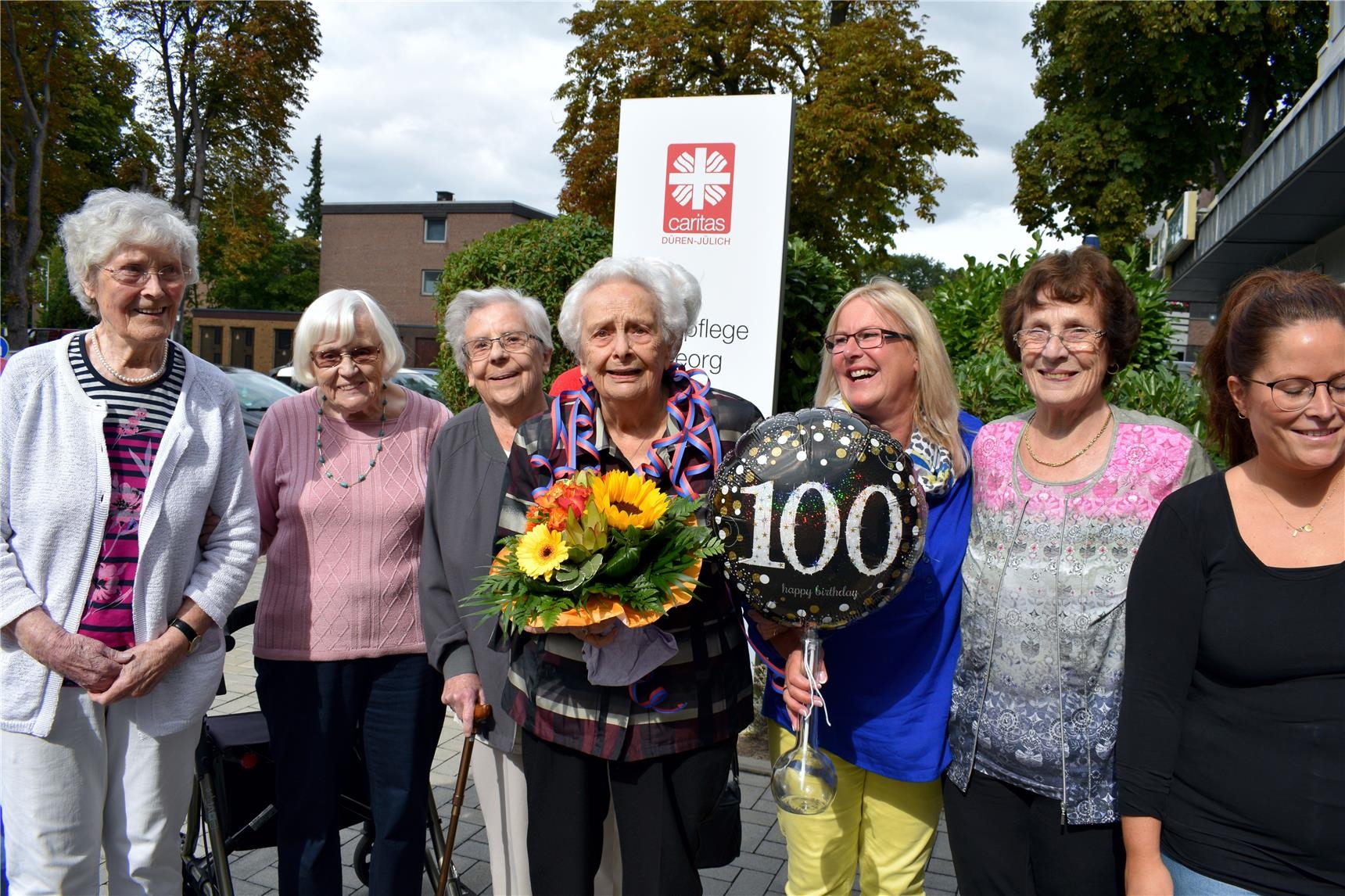 100-jährige mit Gruppe älterer Damen und Blumenstrauß (Erik Lehwald)