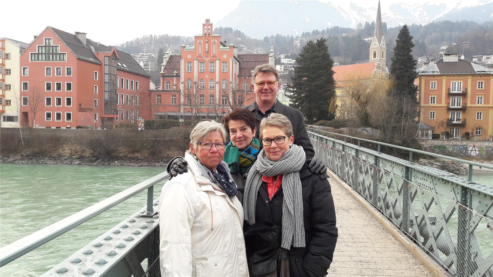 Drei Frauen und ein Mann auf Brücke vor historischen Gebäuden (Peter Nagel)