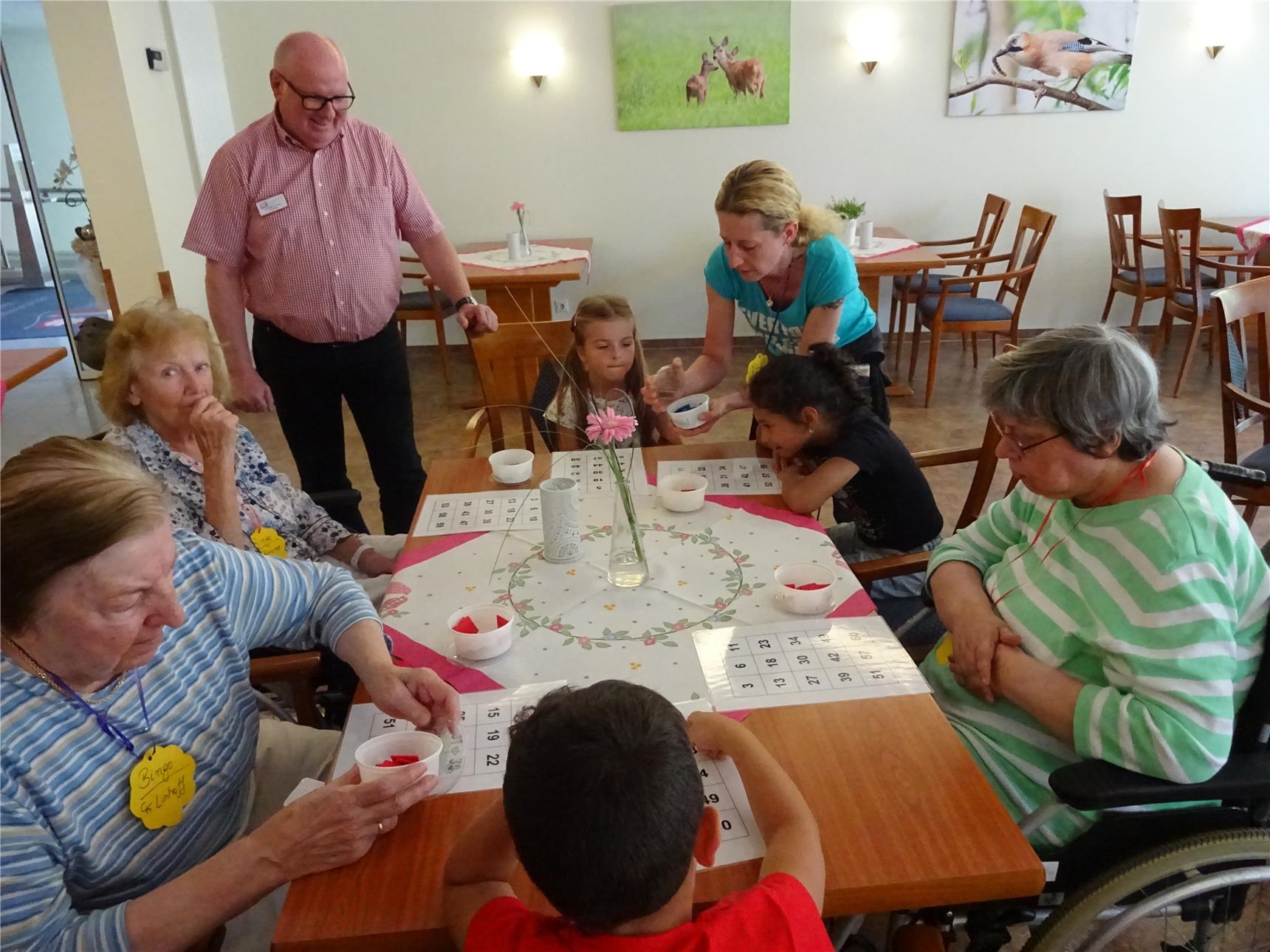 Seniorinnen sitzen mit Kindern am Tisch und spielen Bingo (Seniorenzentrum St. Bonifatius)