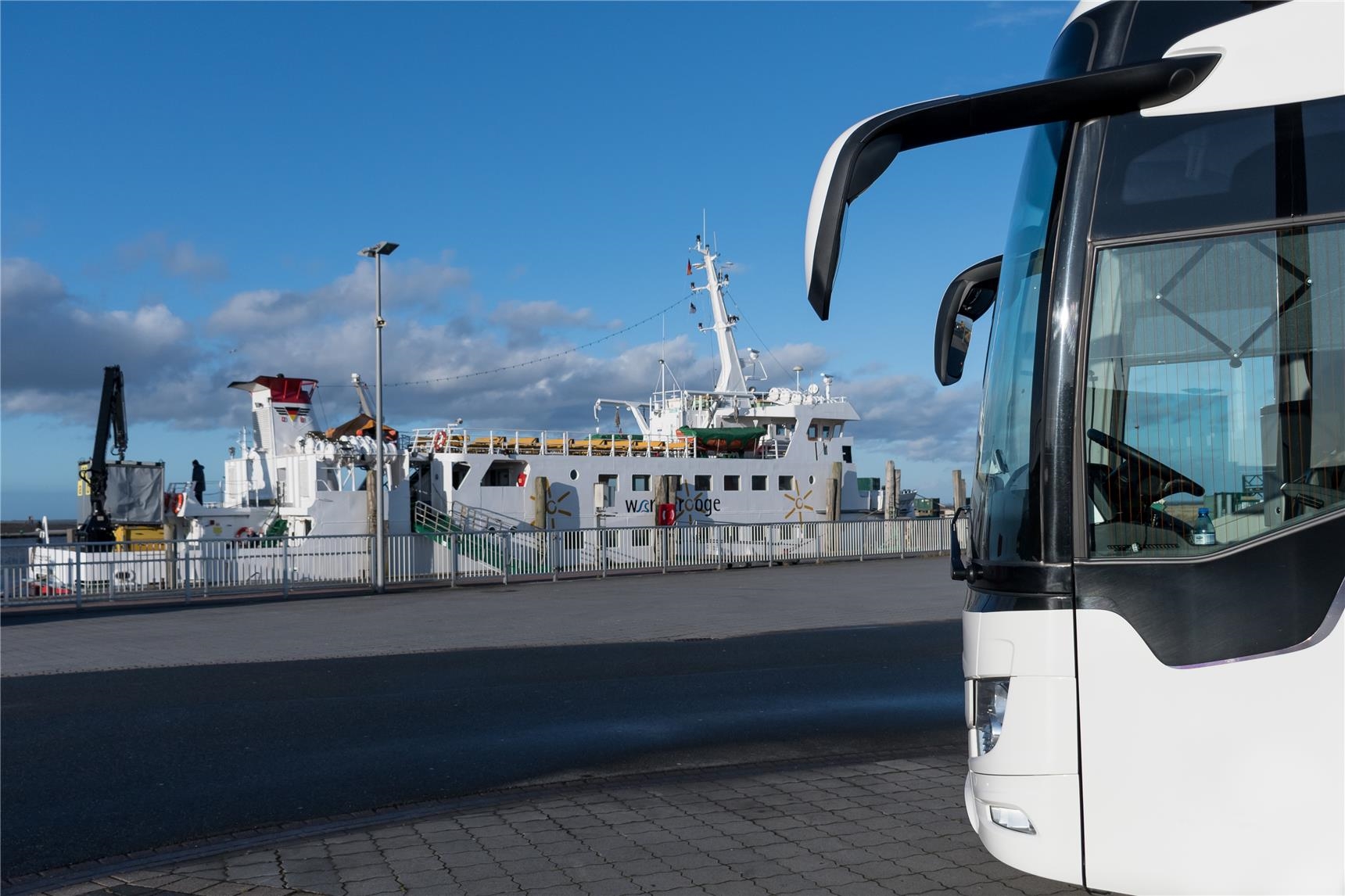 Ein Reisebus steht am Hafen vor einer Fähre. 