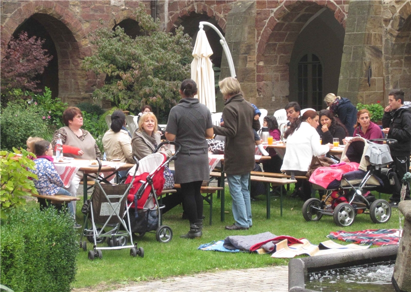 Menschen verschiedener Altersstufen picknicken in einem schönen grünen Innenhof. (Susanne Leimbach)
