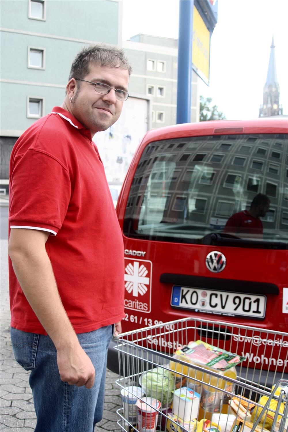 Mann mit vollem Einkaufswagen vor Caritas-Wagen (Foto: Caritasverband Koblenz)