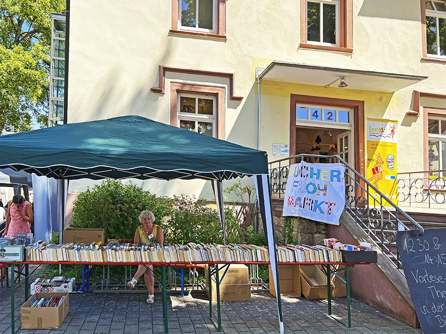 Unter einem Pavillon betreut eine Frau einen Bücherflohmarkt (Caritasverband Darmstadt e. V. / Jens Berger)