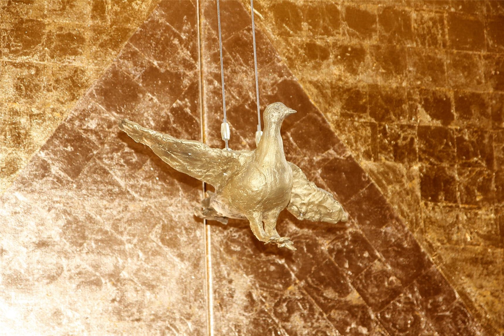 Die Taube als Zeichen des Heiligen Geistes hängt vor dem goldenen Altarbild mit dem Dreieck als Symbol der Dreifaltigkeit Gottes.  (Bernhard Gattner)