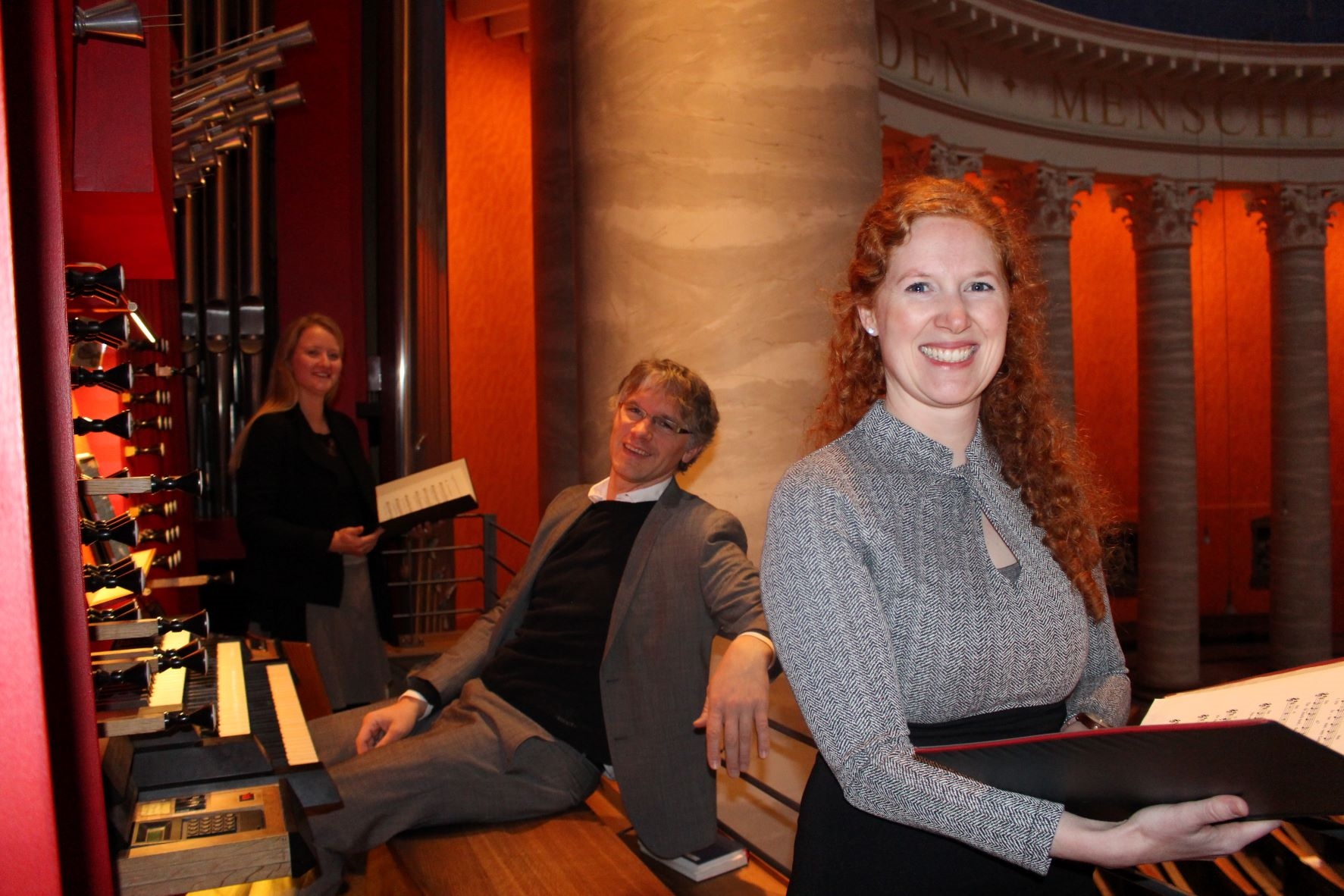 Ein Mann und zwei Frauen vor einer Orgel. (Caritasverband Darmstadt e. V.)