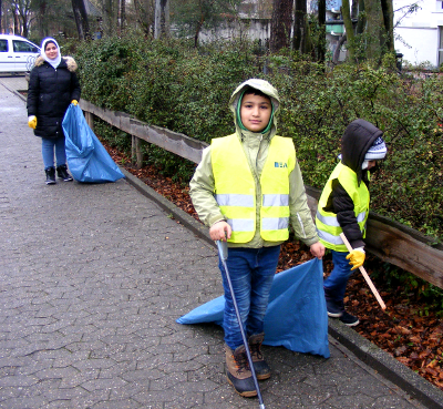 Zwei Kinder mit Sicherheitswesten und eine Helferin mit Müllsack (Caritasverband Darmstadt e. V. / Ulrike Grünig)