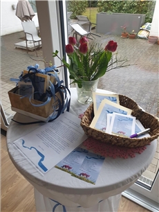 Auf einem ganz in Blau gehaltenen Tisch stehen Karten, ein Frühlingsstrauß, Stifte ein Korb mit blauen Bändern. / Vera Thöne