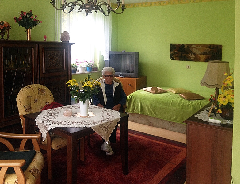 Bewohnerin in ihrer gemütlich eingerichteten Wohnung mit lindgrünen Wänden. 