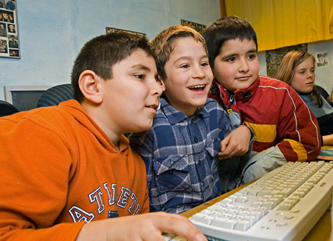 Drei Jungen sitzen vor eine Computer eng zusammen. Vor Ihnen liegt eine Tastatur, im Hintergrund sitzt ein Mädchen an einem weiteren Computer. (Foto: Achim Pohl)