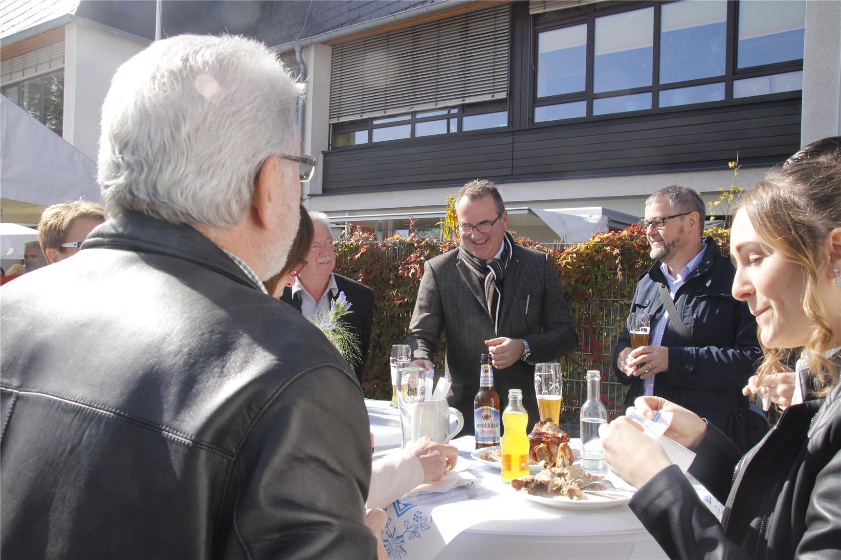 Gäste stehen an einem hohen Tisch bei Getränken und bayrischen Spezialitäten 