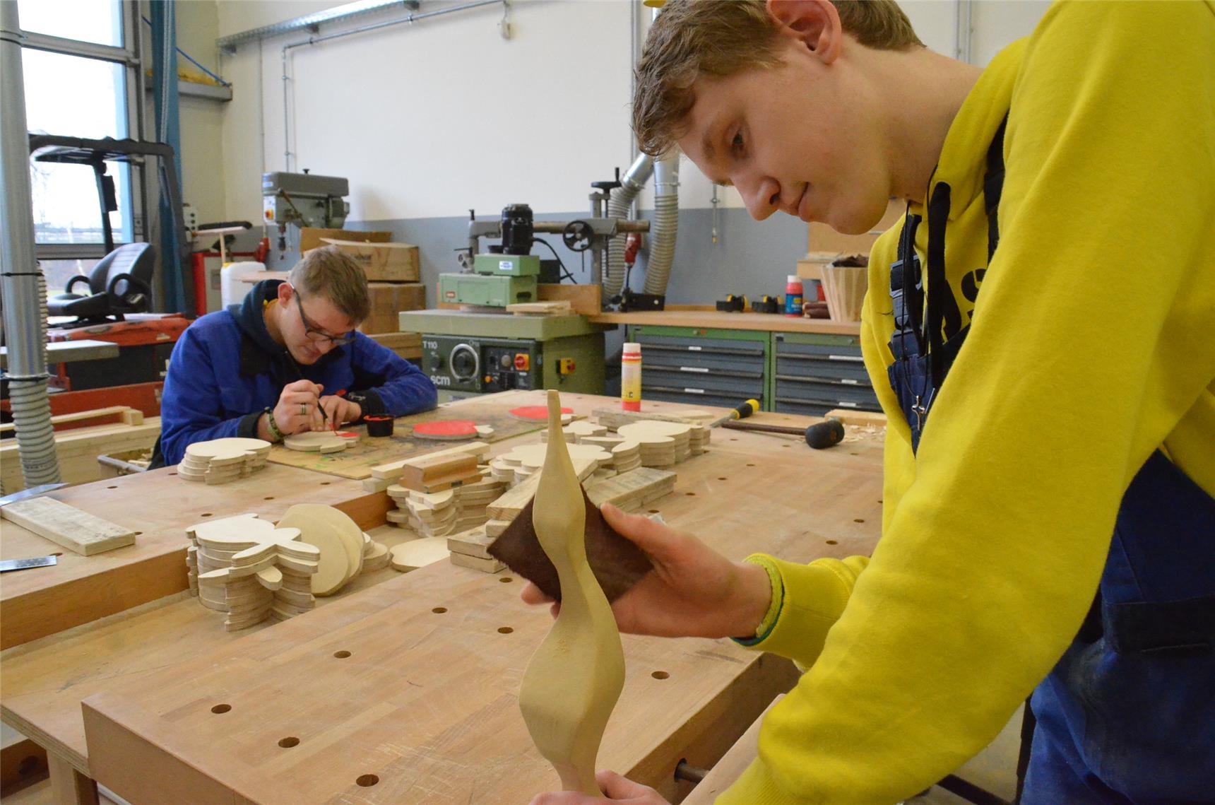 Junger Mann bearbeitet einen kunstvoll gedrechchselten Holzstab mit Schleifpapier (Bild: Eden / Lukas-Heim)