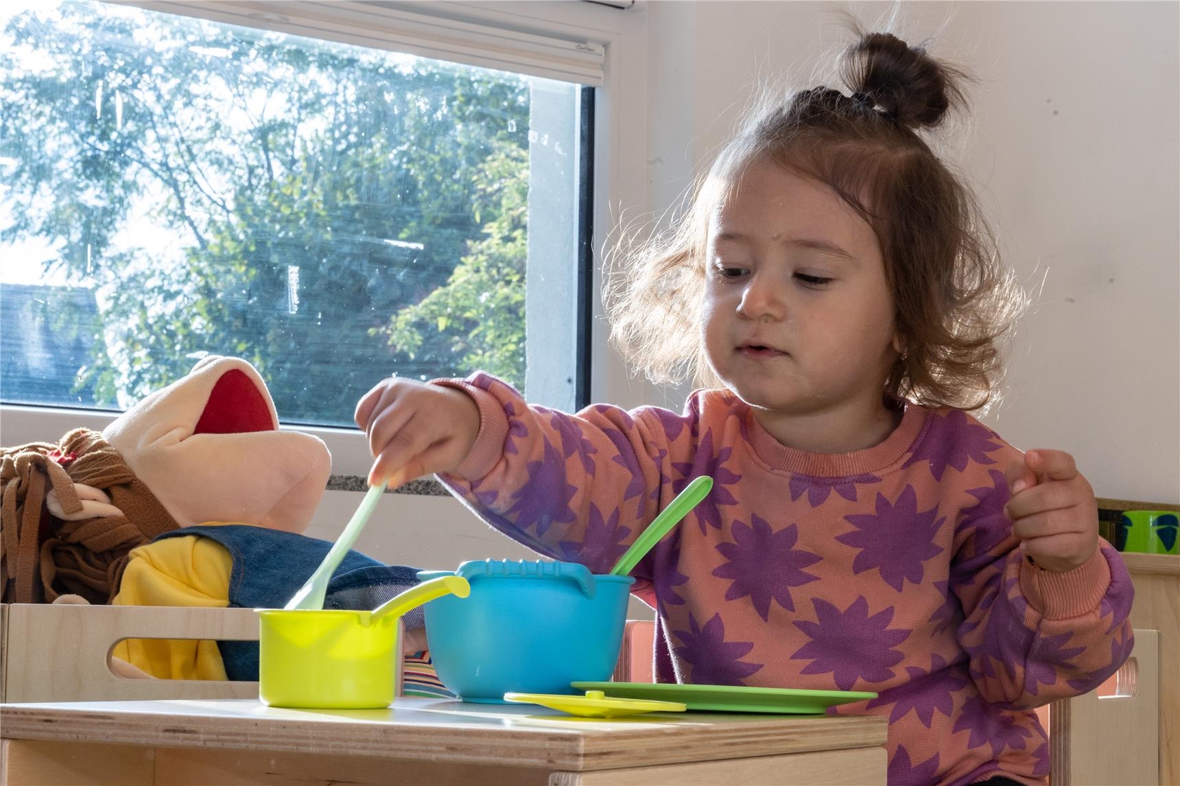 Mädchen spielt in Spielküche mit Töpfen. 