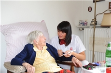 Pflegerin reicht älterer Dame ihre Tabletten / DCV/KNA