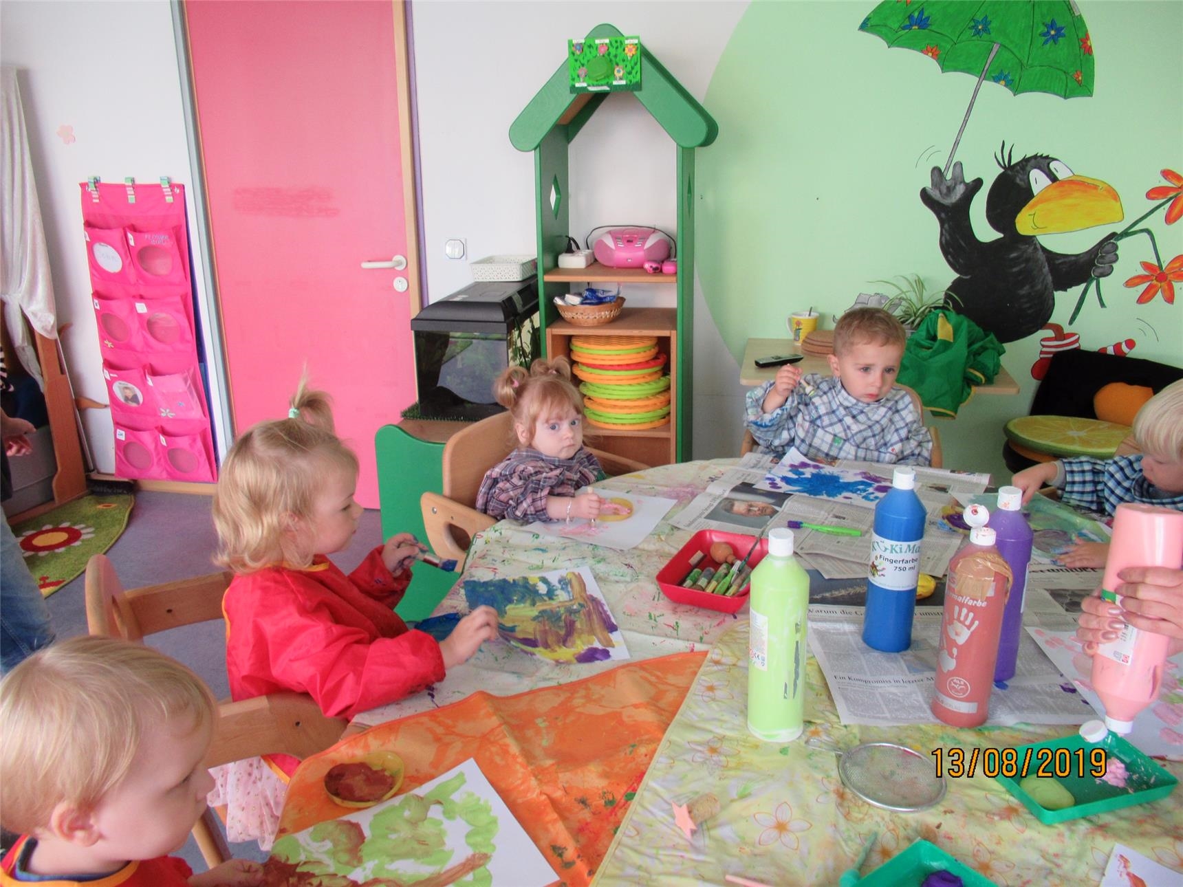 Kinder sitzen am Tisch in ihrem Gruppenraum und malen 