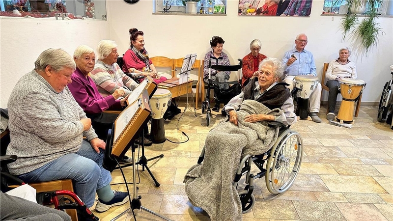 Frauen und ein Mann sitzen im Kreis um eine Frau im Rollstuhl