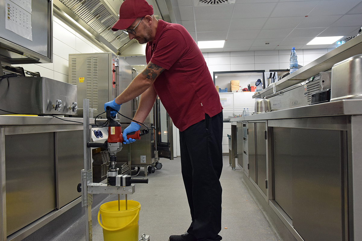 Ein Mitarbeiter der CBW steht in einer Küche und rührt mit einer Rührmaschine Honig in einem gelben Eimer (Foto: Thomas Hohenschue)