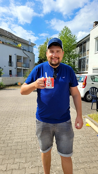 Ein Mann hält froh eine Tasse mit Caritas-Aufdruck in der Hand (Caritasverband Darmstadt e. V.)