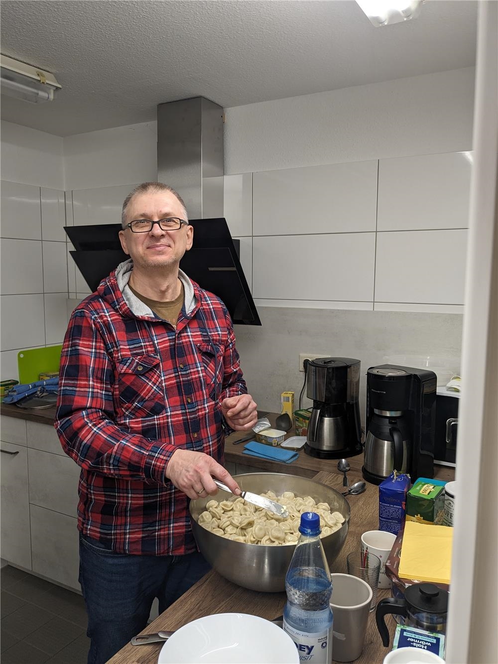 Ein Mann steht an einem großen Topf und kocht Pelmenis 