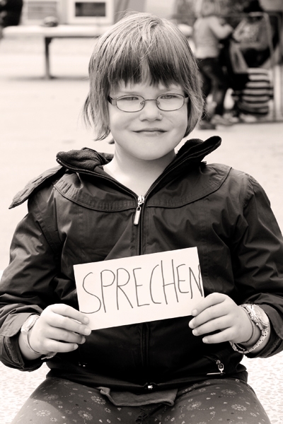 Theresa (8) an der Johann-Joseph-Gronewald-Schule in Köln. Er hält ein Schild mit der Aufschrift "Sprechen". Die Aufnahme ist in schwarz-weiß. (Tanja Anlauf (Fotoprojekt „Unsere Zukunft“) )