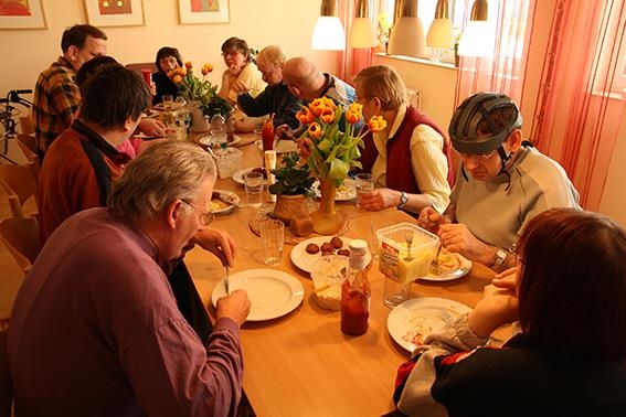 Bewohner essen gemeinsam an einem langen Tisch 