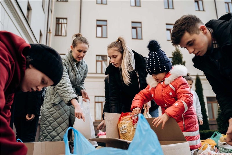 In der Ukraine holen Frauen und Kinder Lebensmittelpackungen aus Kartons
