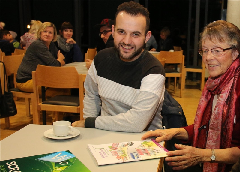 Ein Mann sitzt mit einer Frau am Tisch und sie lächeln