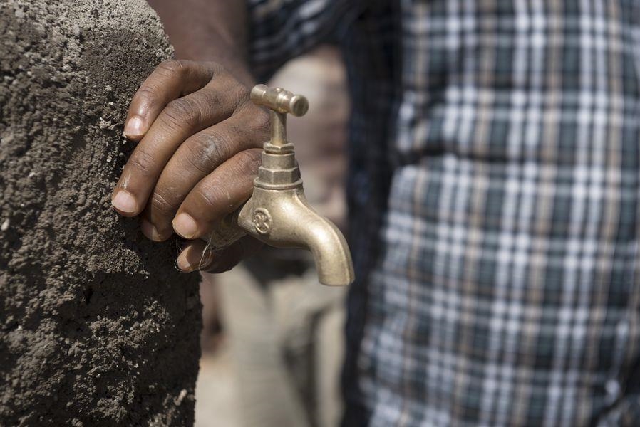 Ein Hand und ein geschlossener Wasserhahn (Christoph Gödan, Caritas international)
