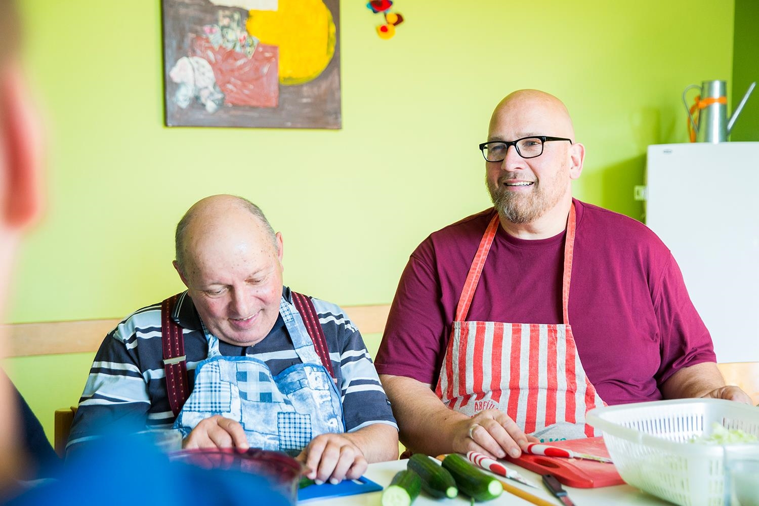 Ein Ehrenamtlicher und ein Mann mit Behinderung sitzen in der Küche und schneiden Gemüse (Deutscher Caritasverband e. V. / Sebastian Pfütze)