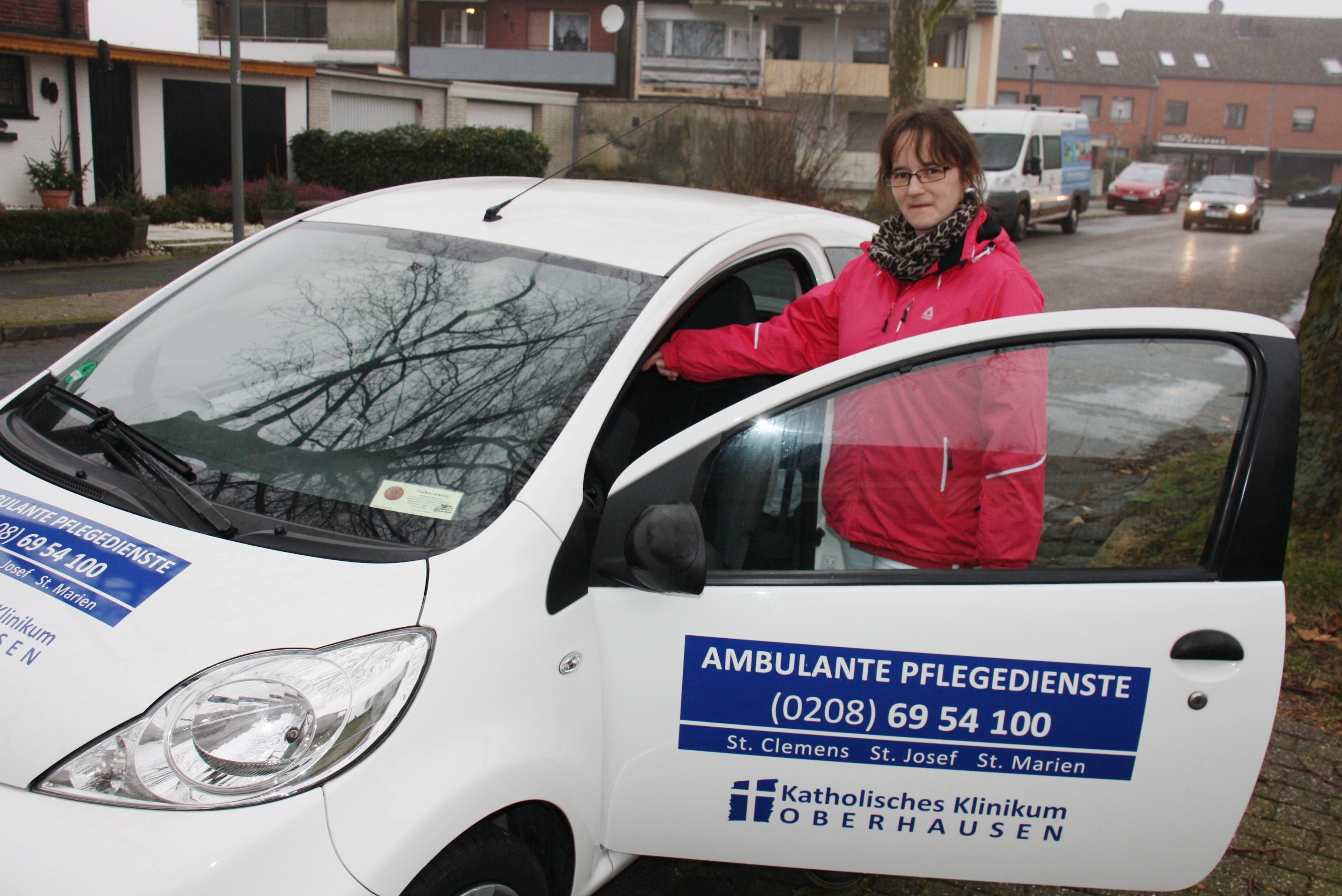 Patricia Röhl vor dem Auto der ambulanten Pflegedienste  (Ulrich Wilmes / Caritas Bistum Essen)