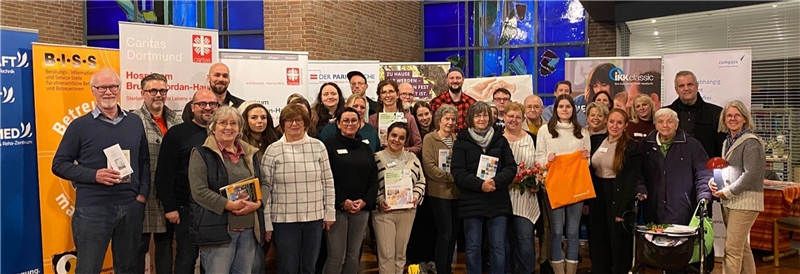 Eine Gruppe Menschen steht vor verschiedenen Roll-Ups und bannern in einer Kirche.