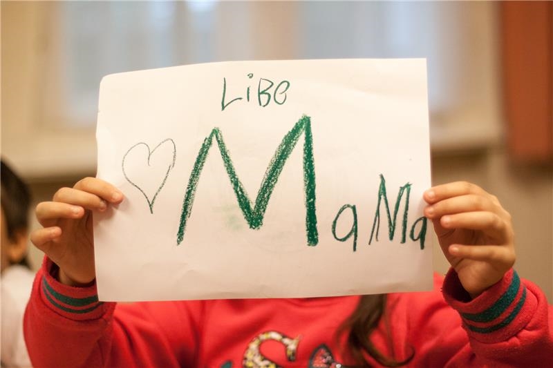Kind hält ein gemaltes Schild mit "Liebe Mama" (Walter Wetzler)