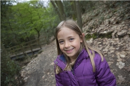 Ein Mädchen steht auf einem Waldweg und lächelt / Dietmar Wäsche