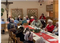 Gemütlich sitzen die Bewohnerinnen und Bewohner im Speisesaal zusammen bei einer sehr besinnlichen Weihnachtsfeier
