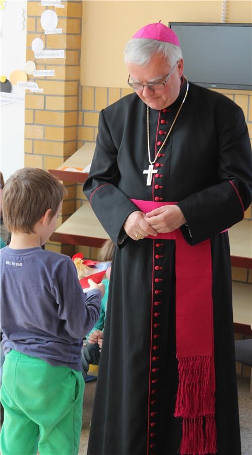 Ein Kindergartenkind übergibt dem Bischof ein Geschenk. (Caritasverband Leipzig e. V.)