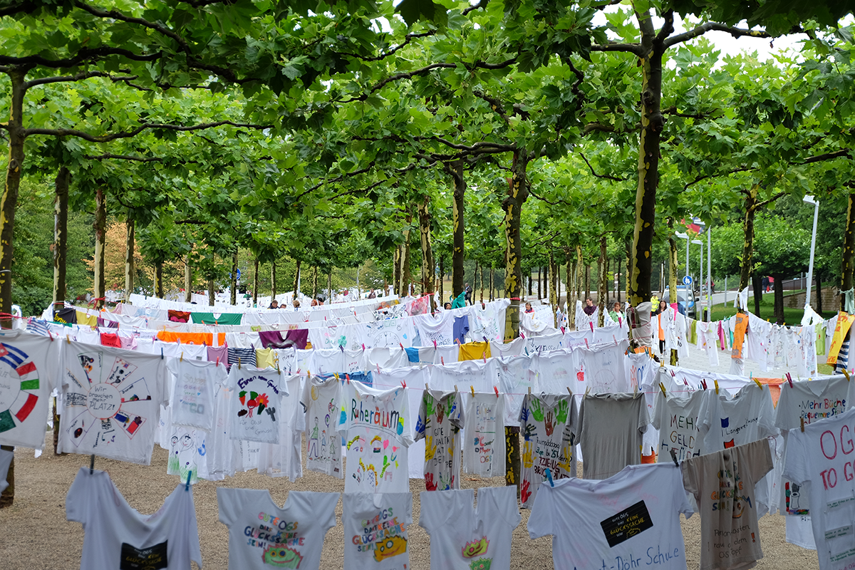 Viele weiße T-Shirts die anlässlich der OGS-Kampagne der LAG FW NRW bedruckt bzw. bemalt und an Wäscheleinen zwischen Bäumen auf der Landtagswiese aufgehängt wurden (Markus Lahrmann)