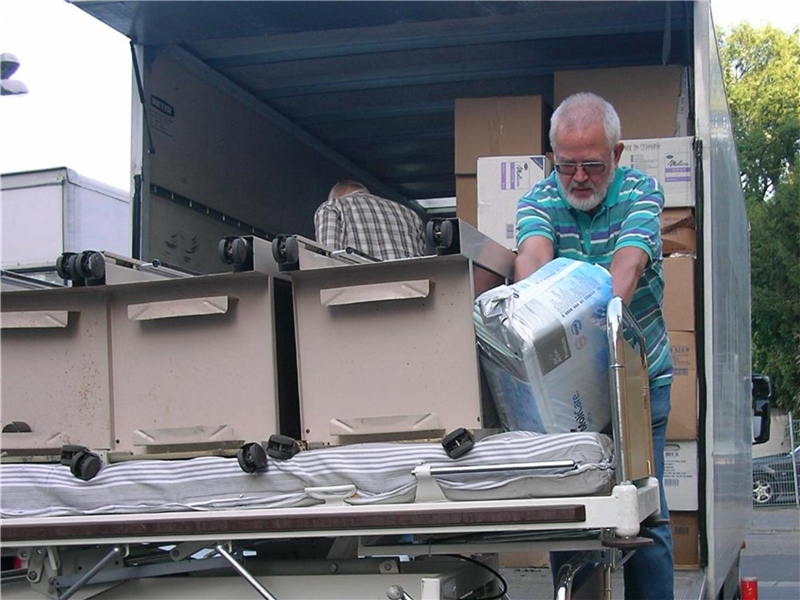 Ein Mann bepackt einen LKW mit Hilfsgütern und Krankenhausbetten.