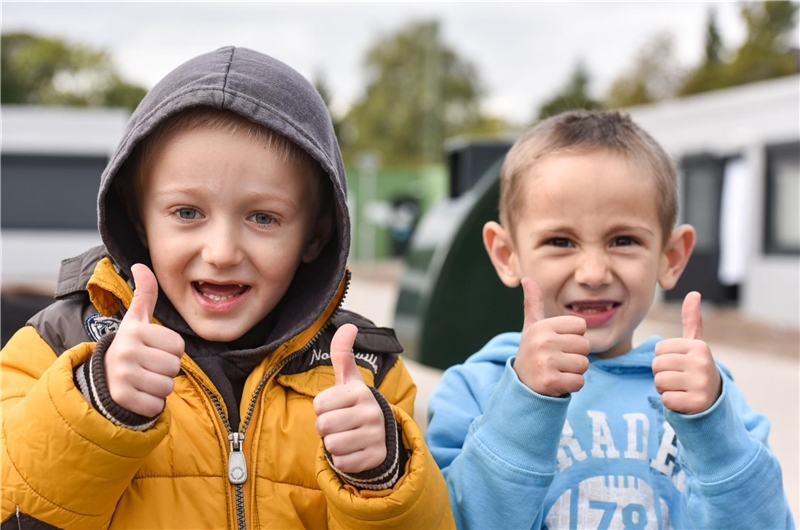 Zwei Jungen zeigen beide Daumen nach oben und lächeln.