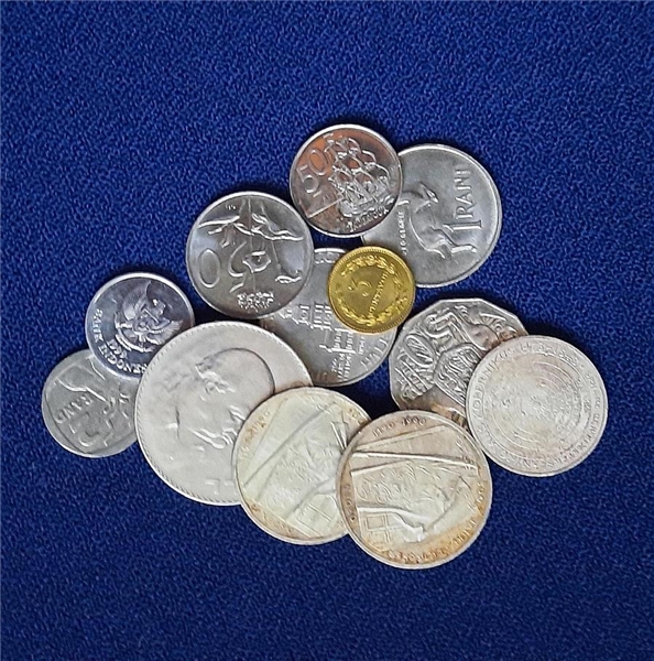 Viele ausländische Münzen liegen auf einem blauen Tuch.