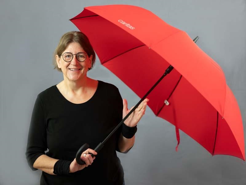 Andrea Hniopek mit aufgespanntem rotem Caritas-Schirm