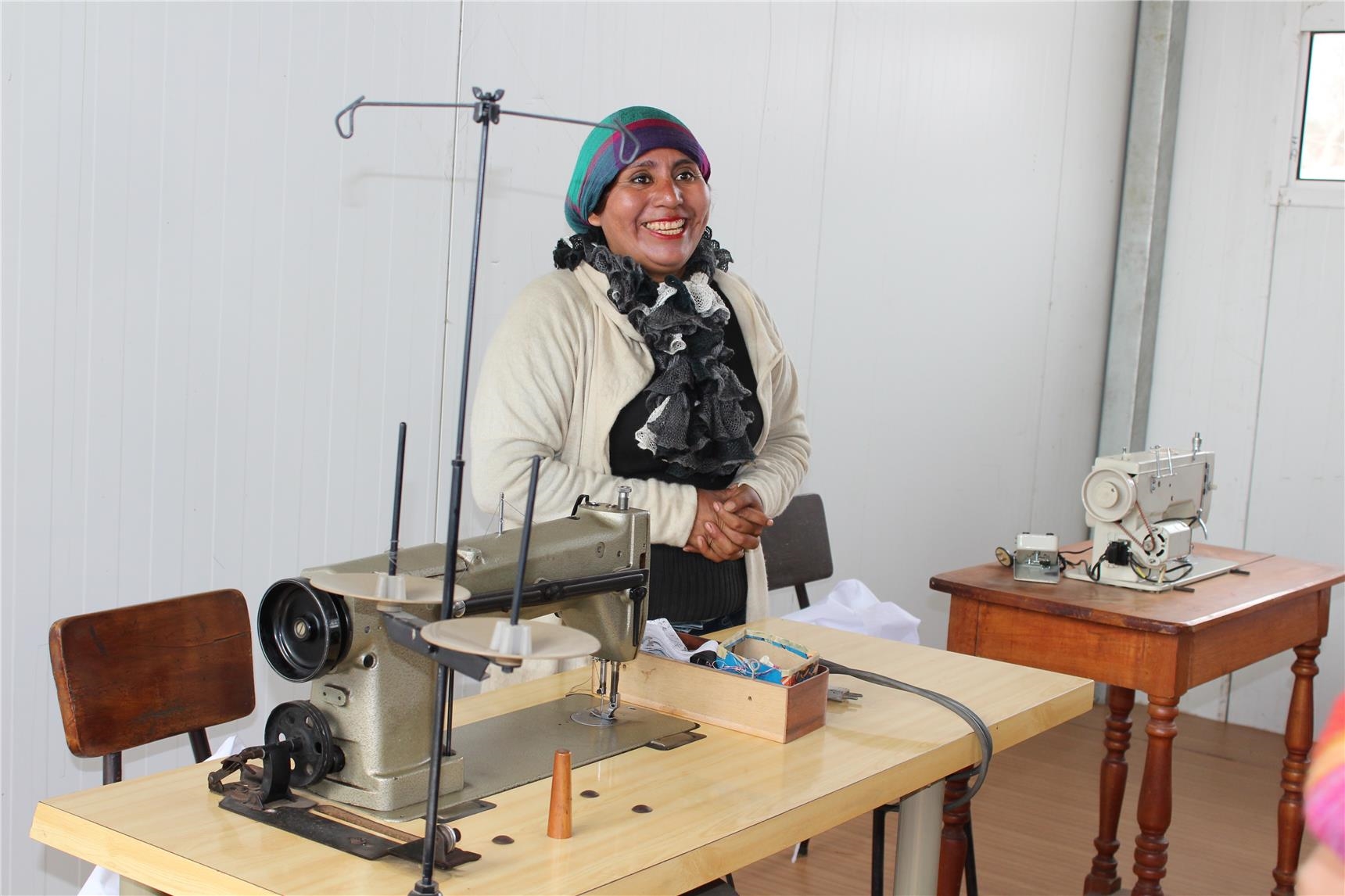 Eine Peruanerin steht stolz hinter Ihrer Nähmaschine.  (Foto: Caritas international / Julia Gaschik)