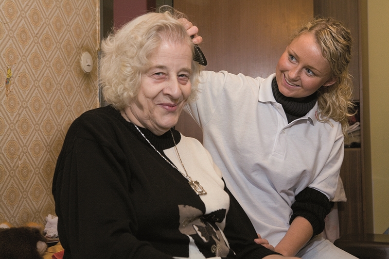 Eine Pflegekraft kämmt einer Seniorin die Haare  / Foto: Lindner