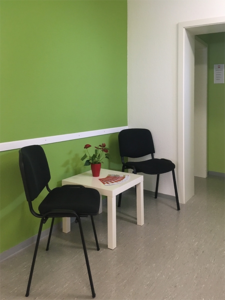 Wartebereich mit zwei Stühlen und einem Tischchen, auf welchem sich Blumen und Flyer befinden (Caritasverband Darmstadt e. V.)