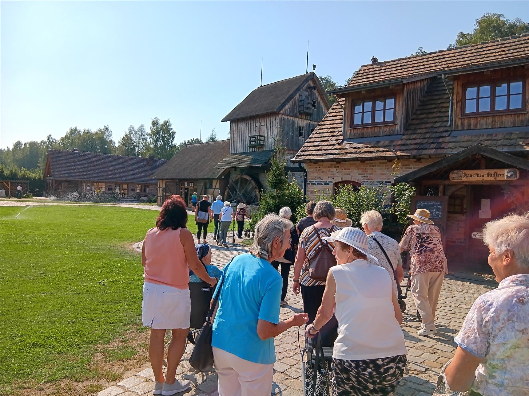 Senioren laufen über einen gepflasterten weg, im Hintergrund ist eine Mühle erkennbar