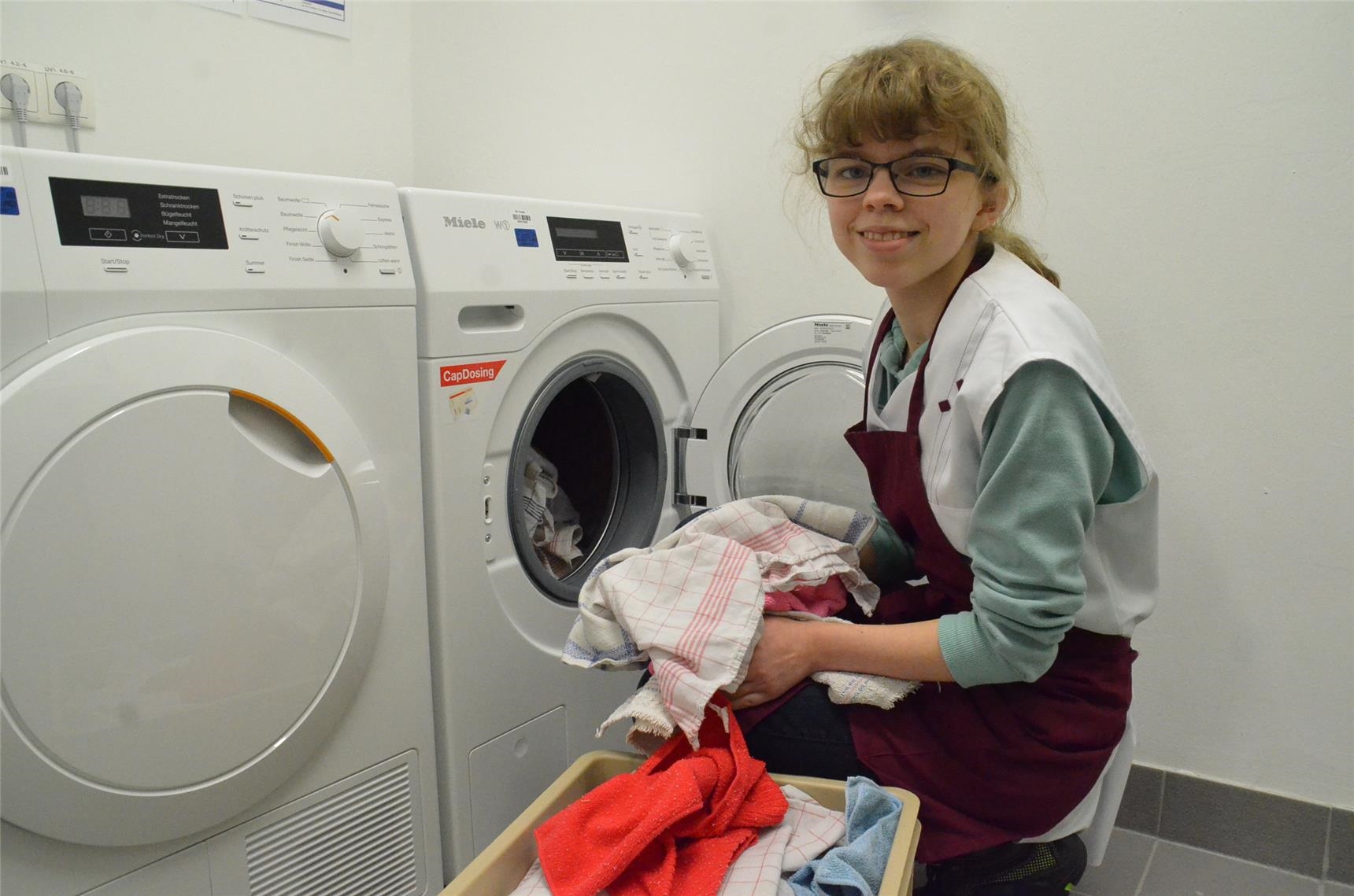 Junge Frau holt Wäsche aus einer Waschmaschine (Bild: Eden / Lukas-Heim)
